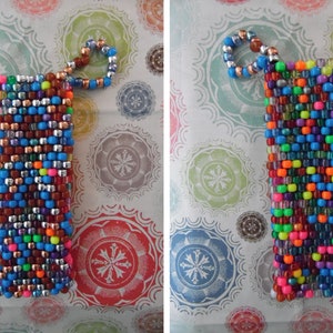 May include: A rectangular beaded phone case in a vibrant mix of colors, including blue, silver, brown, and neon hues. The case has a loop at the top made of smaller beads. This accessory is designed to protect a phone.