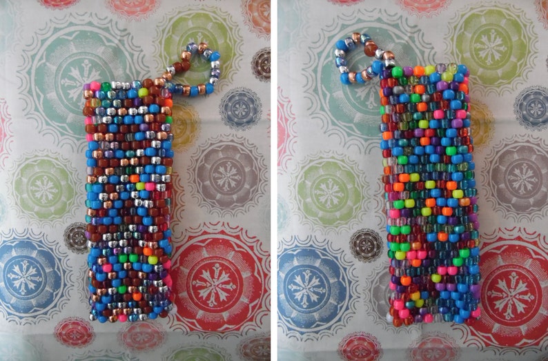 May include: A rectangular beaded phone case in a vibrant mix of colors, including blue, silver, brown, and neon hues. The case has a loop at the top made of smaller beads. This accessory is designed to protect a phone.