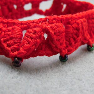 May include: Red crocheted bracelet with green and black beads.