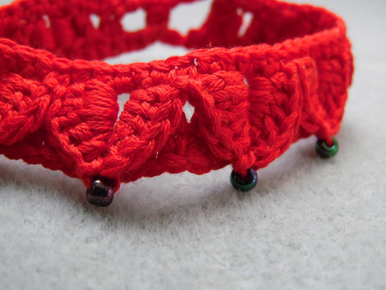 May include: Red crocheted bracelet with green and black beads.