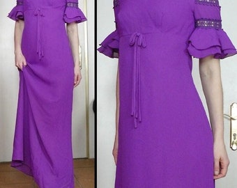 Könnte beinhalten: Ein leuchtend lila Maxikleid mit kurzen, gerüschten Ärmeln und einer taillierten Taille. Das Kleid hat einen runden Ausschnitt und ein Bindedetail an der Taille. Die Ärmel haben eine dekorative Spitzenborte. Geeignet für formelle Anlässe.
