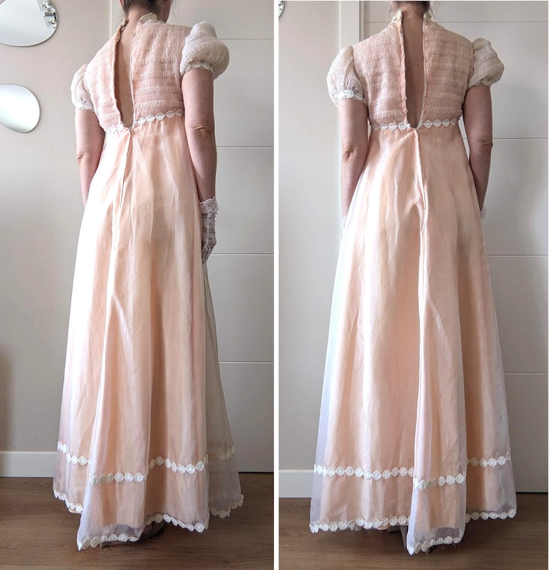 K&ouml;nnte beinhalten: Ein vintage-farbenes Pfirsichkleid mit hohem Ausschnitt und Schl&uuml;sselloch-R&uuml;cken. Das Oberteil hat einen strukturierten Strickstoff mit kurzen, gepufften &Auml;rmeln. Der Rock ist ein flie&szlig;endes, transparentes Material mit wei&szlig;er Spitzenborte am Saum. Das Kleid ist ein klassisches, elegantes Design.