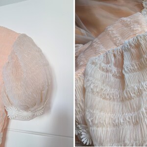 K&ouml;nnte beinhalten: Vintage pfirsichfarbenes Kleid mit transparenten, gepufften &Auml;rmeln. Das Kleid hat einen zarten wei&szlig;en Spitzkragen und eine G&auml;nsebl&uuml;mchen-f&ouml;rmige Verzierung am Saum und an den Manschetten. Der Stoff hat ein strukturiertes, geknittertes Aussehen.