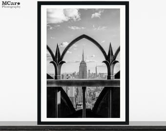 Peut inclure: Photographie en noir et blanc de l'Empire State Building à New York, vue à travers une clôture en fer forgé.