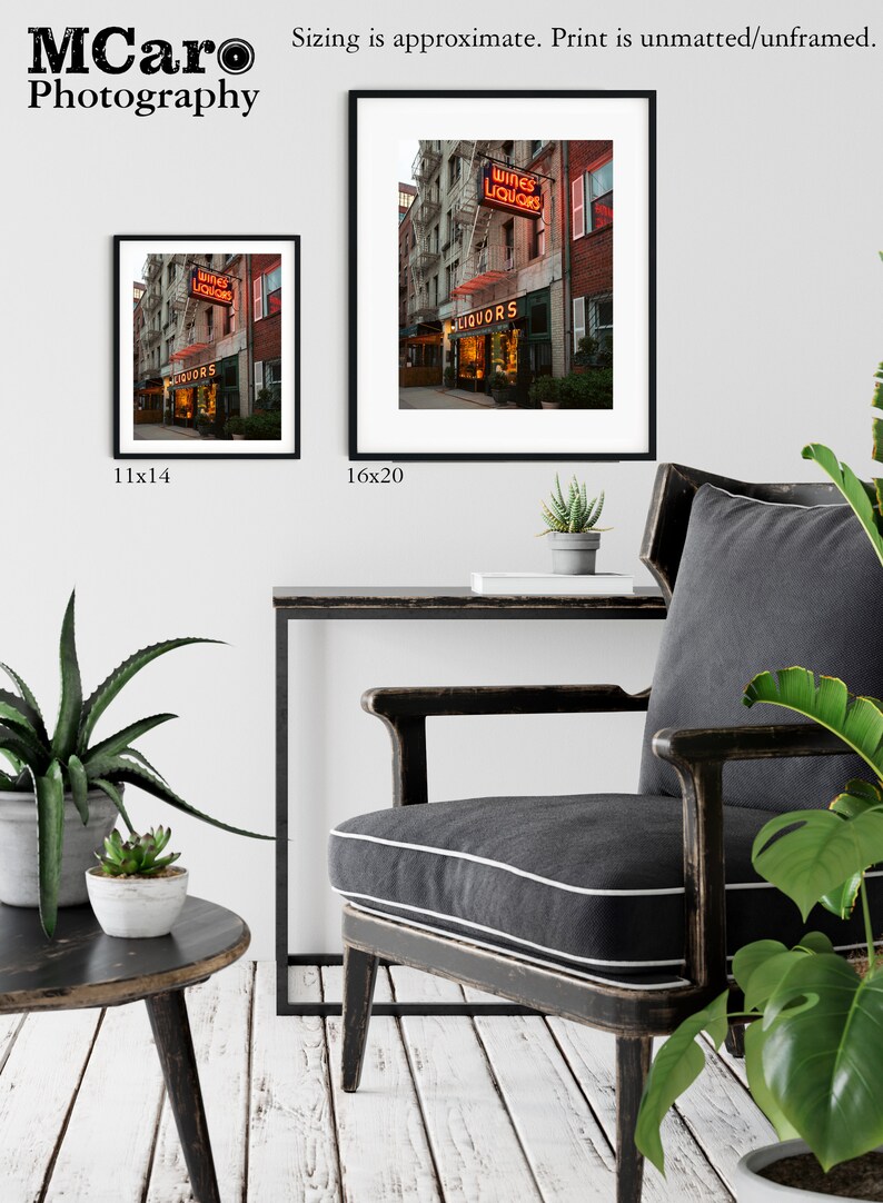 May include: A photograph of a vintage storefront with a neon sign that reads "Wines Liquors". The storefront is located on a city street with brick buildings and a fire escape. The photo is available in two sizes: 11x14 inches and 16x20 inches.