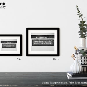 May include: Two black framed prints of a black and white photo of a sign that reads "MADISON SQUARE GARDEN" with an arrow pointing to the right. The smaller print is 5x7 inches and the larger print is 8x10 inches.