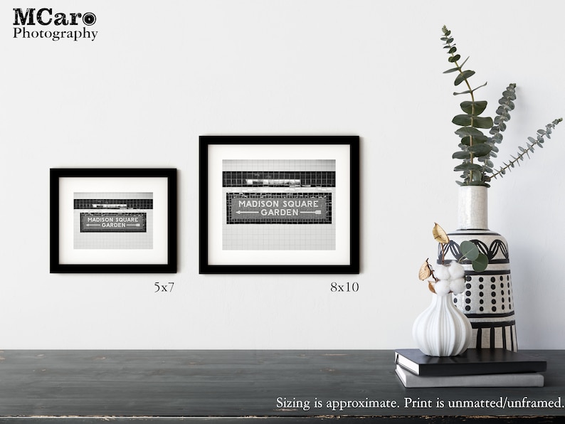 May include: Two black framed prints of a black and white photo of a sign that reads "MADISON SQUARE GARDEN" with an arrow pointing to the right. The smaller print is 5x7 inches and the larger print is 8x10 inches.