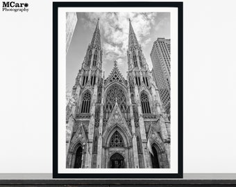 Peut inclure: Une photographie en noir et blanc d'une grande église ornée avec deux flèches imposantes. L'église est située dans une ville et est entourée d'autres bâtiments.