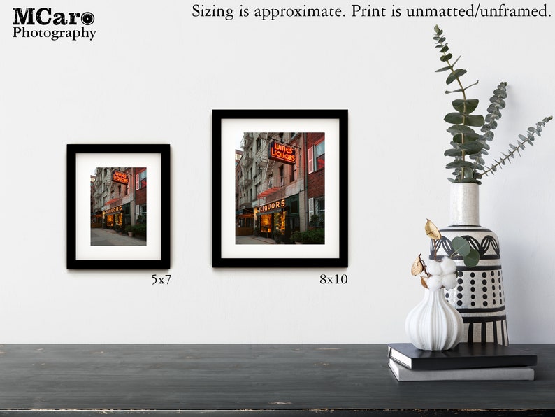 May include: Two framed photographs of a city street scene with a neon sign that reads "Wines Liquors". The smaller photo is 5x7 inches and the larger photo is 8x10 inches.