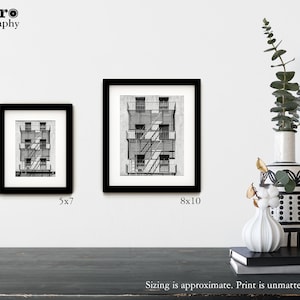 May include: Two black framed prints of a black and white drawing of a building with a fire escape. The smaller print is 5x7 inches and the larger print is 8x10 inches.