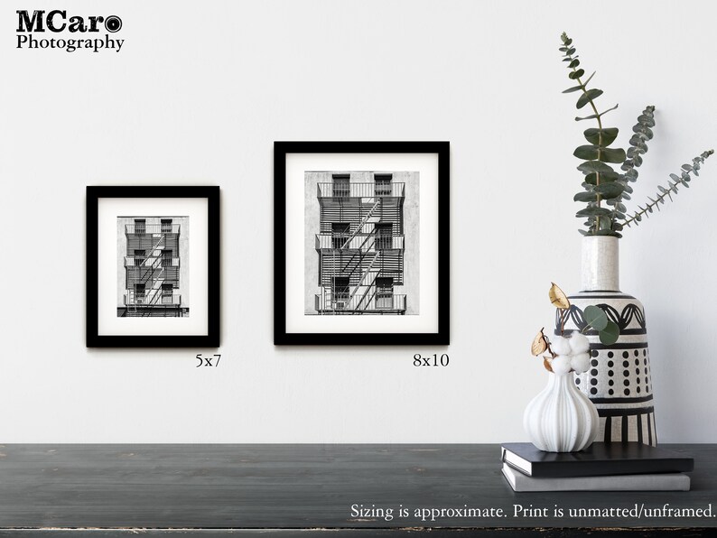 May include: Two black framed prints of a black and white drawing of a building with a fire escape. The smaller print is 5x7 inches and the larger print is 8x10 inches.