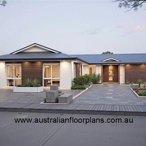 May include: A modern, single-story house with a white exterior, a dark gray roof, and a large driveway. The house has a large front yard with landscaping and a walkway leading to the front door. The house has a large front window and a double front door. The house has a website address on the driveway: www.australianfloorplans.com.au