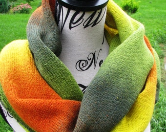 May include: A knitted infinity scarf with a gradient of green, yellow, and orange colors. The scarf is displayed on a mannequin.