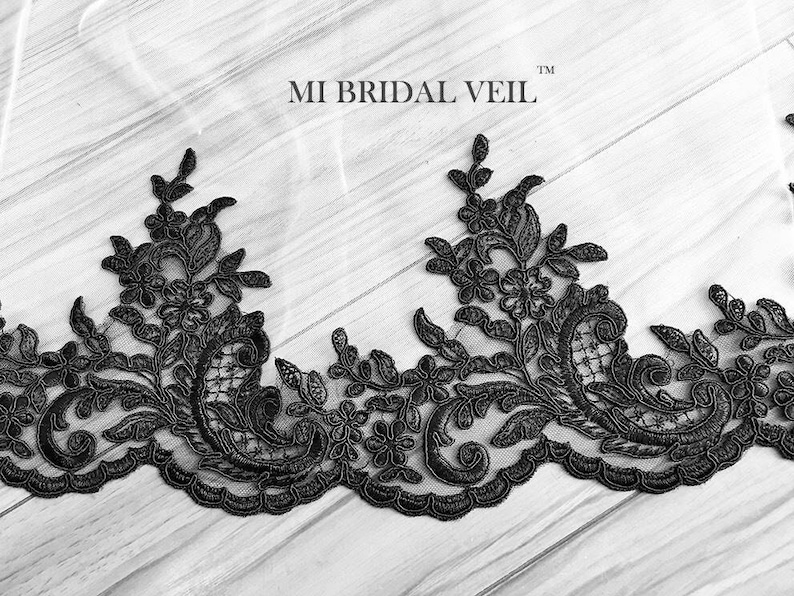 May include: Black floral lace trim with intricate detailing. The lace features a repeating pattern of flowers and leaves, creating an elegant border. The text "MI BRIDAL VEIL" is visible in the image.