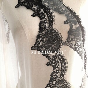 May include: Close-up of a bridal veil with intricate black lace detailing. The lace features floral patterns and a scalloped edge, creating a delicate and elegant design. The text "MI BRIDAL VEIL" is visible.