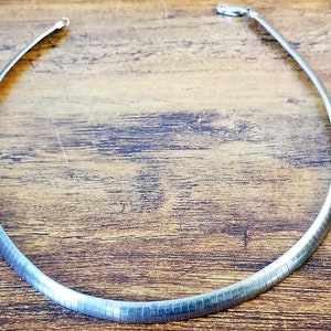 May include: A silver chain necklace with a simple, sleek design. The chain is made of a smooth, shiny metal and has a classic, timeless look.