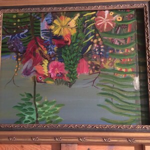 May include: A framed painting depicting a lush, tropical scene with vibrant flowers in shades of red, pink, yellow, and purple. The flowers are surrounded by green foliage and a blue sky in the background.