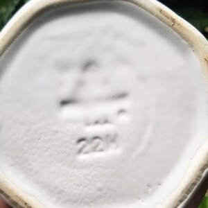 Puede incluir: Plato octogonal de cer&aacute;mica blanca con un borde elevado. La parte inferior del plato tiene un sello negro que dice "22H".