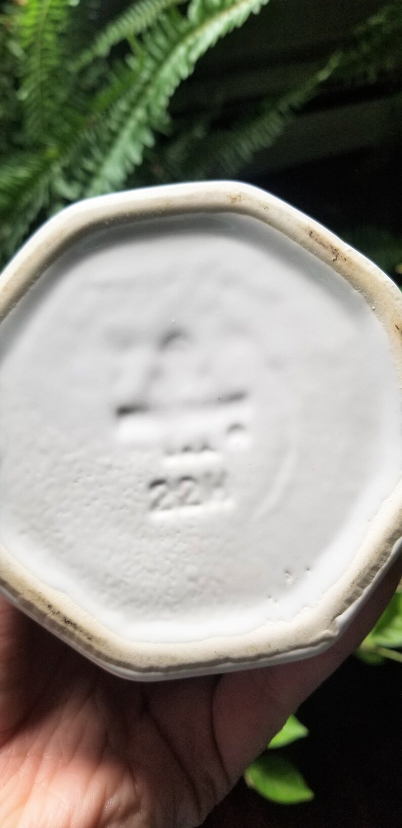Puede incluir: Plato octogonal de cer&aacute;mica blanca con un borde elevado. La parte inferior del plato tiene un sello negro que dice "22H".