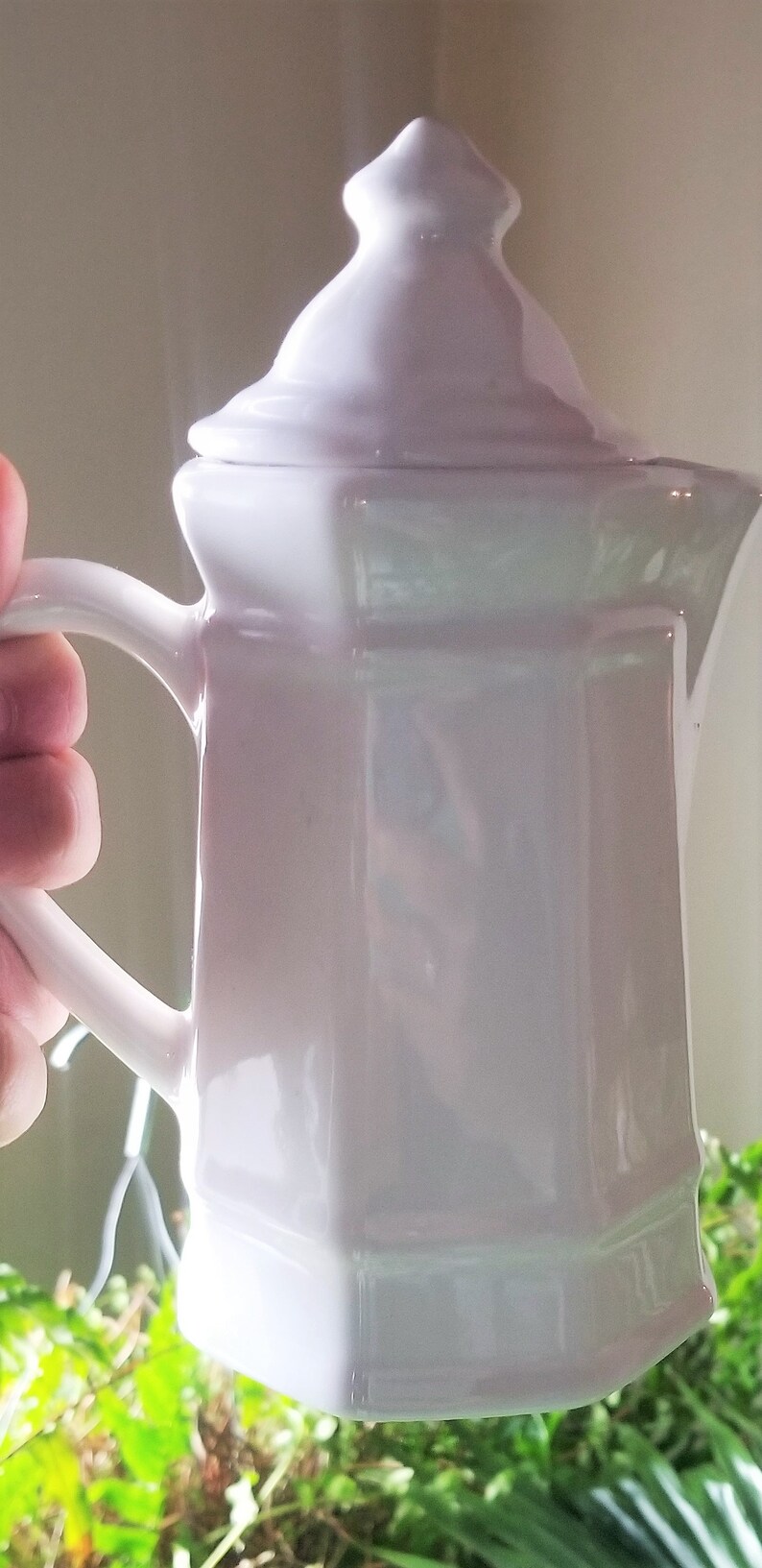 Puede incluir: Una tetera de cer&aacute;mica blanca con tapa y asa. La tetera tiene un cuerpo redondeado y una base cuadrada.