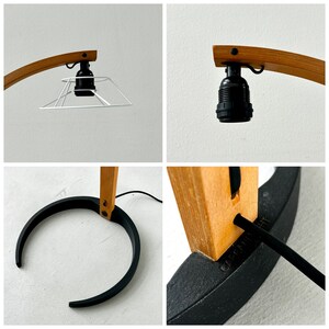 K&ouml;nnte beinhalten: Eine Stehlampe aus Holz mit einem schwarzen Metallfu&szlig; und einem wei&szlig;en Lampenschirm. Die Lampe hat ein schlichtes, modernes Design.