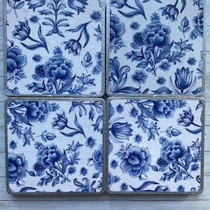 May include: Set of four blue and white floral coasters with a silver trim. The coasters feature a traditional Dutch Delftware design.