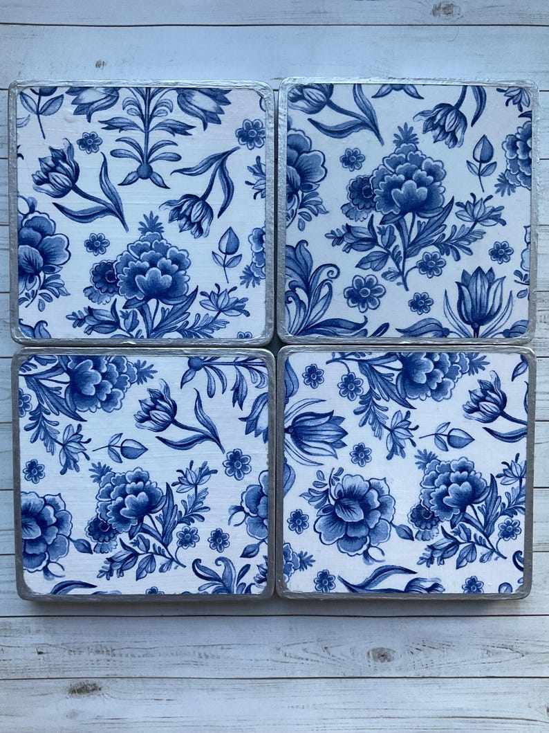 May include: Set of four blue and white floral coasters with a silver trim. The coasters feature a traditional Dutch Delftware design.