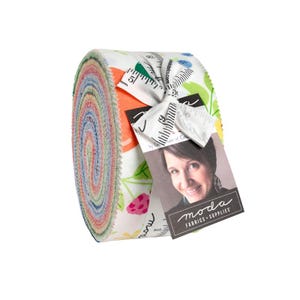 Può includere: Rotolo di tessuto con un colorato motivo floreale. Il tessuto è bianco con accenti arancioni, rosa, verdi e blu. È attaccato un'etichetta con il logo Moda Fabrics e l'immagine di una donna.