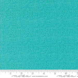May include: Teal fabric with a subtle grid pattern and a slightly textured surface. The fabric is shown with a ruler for scale.
