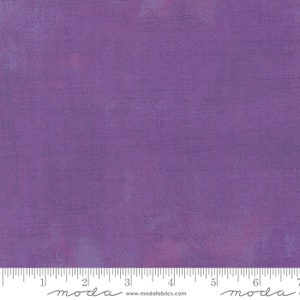 May include: A solid purple fabric with a subtle texture. The fabric is a light purple colour with a slight sheen. The fabric is measured in inches with a ruler at the bottom of the image. The ruler has the word "moda" printed on it.
