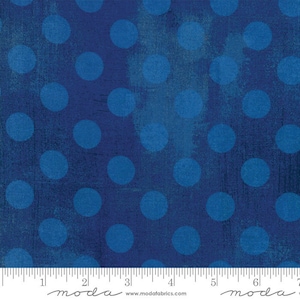 May include: Blue and white polka dot fabric with a textured background. The fabric is measured with a ruler that says "moda" on it.