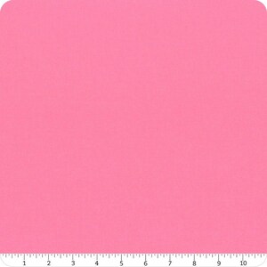 May include: A solid pink fabric with a ruler along the bottom edge. The fabric is a vibrant, bright pink colour. The ruler is marked with numbers and small lines, indicating measurements in inches.