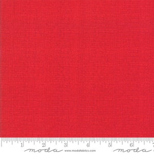 May include: A solid red fabric with a subtle textured pattern. The fabric is measured with a ruler that has the word "moda" printed on it.