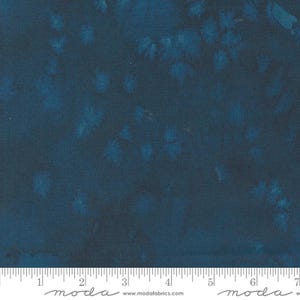 May include: A dark blue fabric with a subtle, faded pattern of white spots. The fabric is textured and has a slight sheen. The fabric is labeled "moda" and has a website address printed on it.
