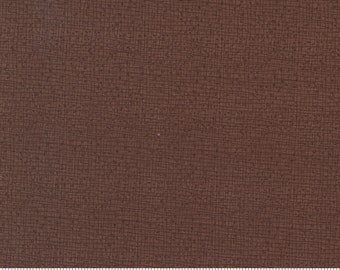 May include: A close-up of a brown fabric with a subtle textured pattern. The fabric is measured with a ruler in inches.