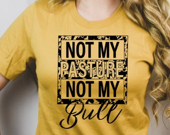 May include: A yellow t-shirt with a black and gold graphic that says "Not My Pasture Not My Bull".