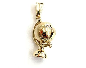 May include: A gold-colored globe pendant charm with a detailed globe design. The globe is on a stand with a loop at the top for attaching to a chain.