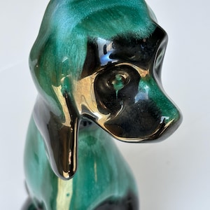 Könnte beinhalten: Keramikhundefigur mit glänzendem Finish. Der Hund ist hauptsächlich türkis und schwarz, mit goldenen Akzenten. Die Figur hat eine glatte, reflektierende Oberfläche und sitzt.