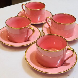 Pu&ograve; includere: Set di quattro tazzine da t&egrave; rosa e piattini con bordo dorato. Le tazzine e i piattini sono tutti della stessa dimensione e forma. Le tazzine hanno una forma arrotondata e un piccolo manico. I piattini sono rotondi e hanno un bordo leggermente rialzato.