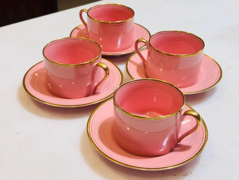 Pu&ograve; includere: Set di quattro tazzine da t&egrave; rosa e piattini con bordo dorato. Le tazzine e i piattini sono tutti della stessa dimensione e forma. Le tazzine hanno una forma arrotondata e un piccolo manico. I piattini sono rotondi e hanno un bordo leggermente rialzato.