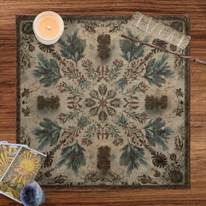 May include: A square altar cloth featuring a symmetrical botanical pattern of pine branches, red berries, and brown pinecones on a cream background, accompanied by a white candle, a sage smudge stick, tarot cards, and a small purple crystal.
