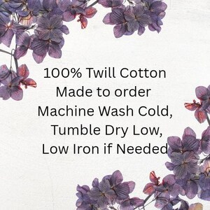 May include: A white background framed by purple hydrangea flowers with black text that reads: 100% Twill Cotton, Made to order, Machine Wash Cold, Tumble Dry Low, Low Iron if Needed. The text provides care instructions for a textile product.