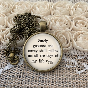 May include: A bronze necklace with a round pendant featuring the text "Surely goodness and mercy shall follow me all the days of my life. Psalm 23:6" on a white background.