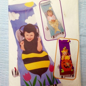 May include: A sewing pattern for a stroller cover with three different designs: a bee, a mermaid, and a pumpkin. The pattern is from Butterick and is size 6301. The pattern is for one size.