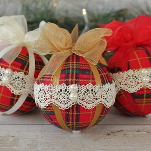 May include: Three red and gold plaid Christmas ornaments with white lace trim and pearl accents. Each ornament has a different colored ribbon bow.