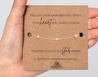 Könnte beinhalten: Ein goldfarbenes Kettenarmband mit drei kleinen Sternanhängern, präsentiert auf einer rechteckigen braunen Karte mit dem aufgedruckten Text: THOUGH YOUR ARMS MAY FEEL EMPTY, YOUR heart WILL ALWAYS KNOW, YOUR PRECIOUS LITTLE star ABOVE, IS WITH YOU WHEREVER YOU GO.