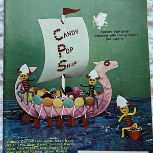 May include: A vintage magazine cover featuring a craft project for a candy pop ship. The ship is made of paper plates and decorated with candy. The cover also includes the magazine's title, "Pack o Fun", and the text "The Only Scrap-Craft Magazine".