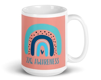 Taza blanca brillante con el mensaje "Amo a alguien con 22q"