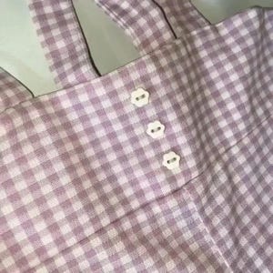 May include: Pink and white gingham fabric with three white buttons.