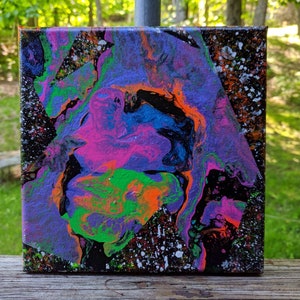 May include: Abstract painting on canvas with swirling patterns in shades of purple, pink, green, blue, orange, and black. The background is black with white speckles.